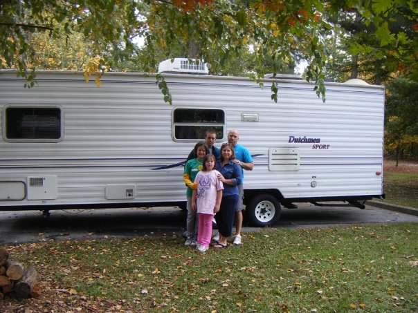 family standing beside camper